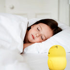 Child sleeping in bed with a yellow duck-shaped night light next to the bed.