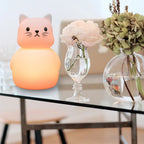 Cat-shaped night light on a table with flowers in the background