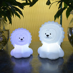 Two lion-shaped night lights on a reflective surface with a blurred background