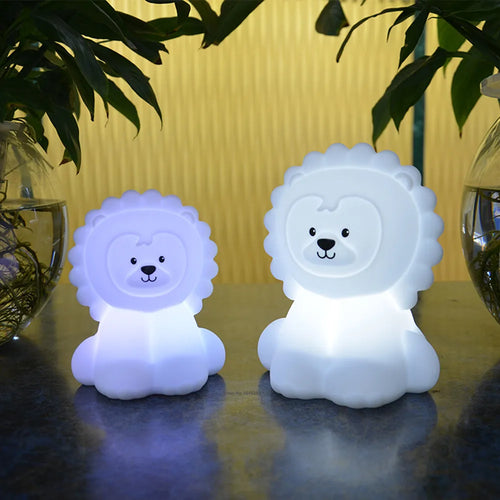 Two lion-shaped night lights on a reflective surface with a blurred background